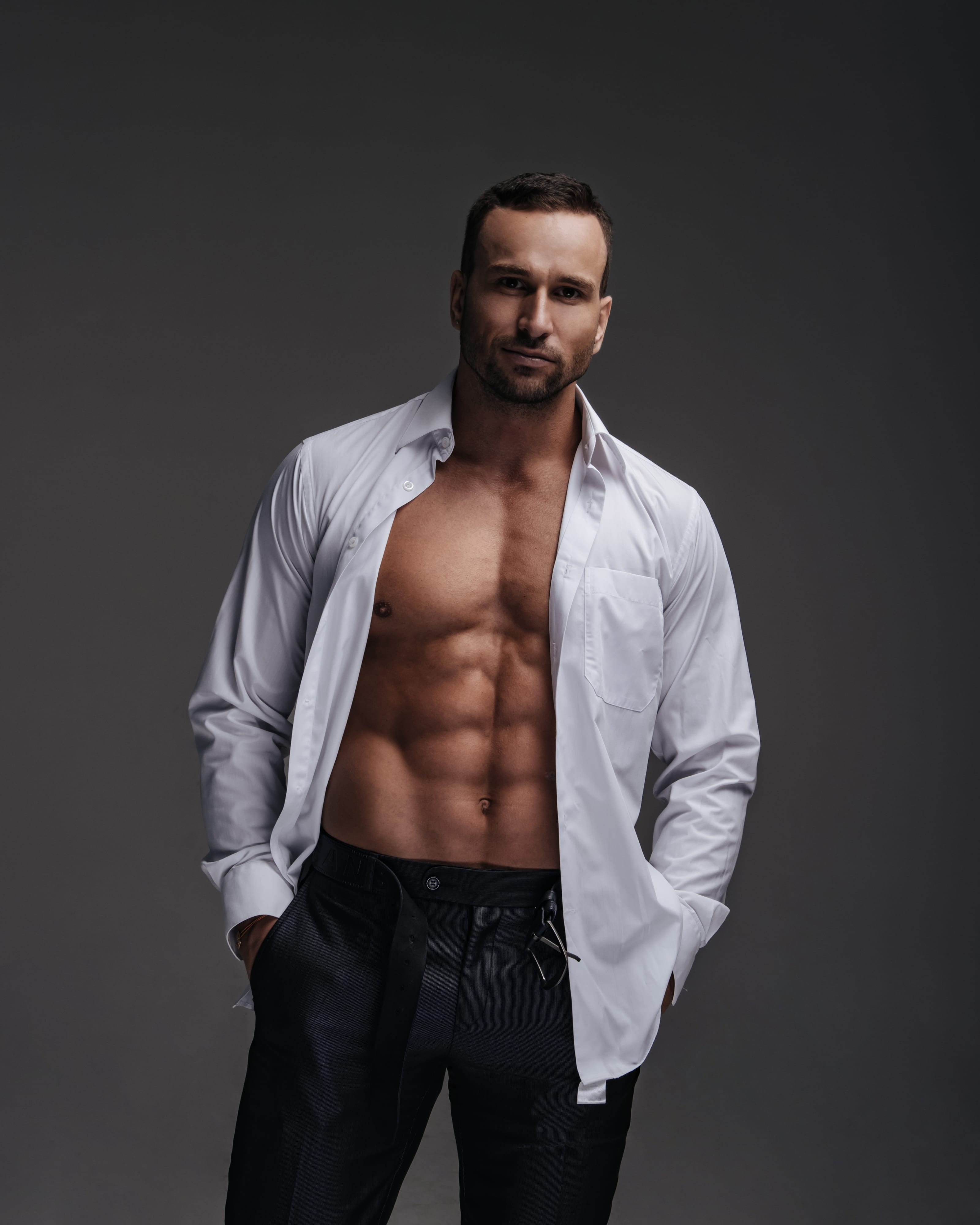 Fit man in an open white shirt showing a defined torso